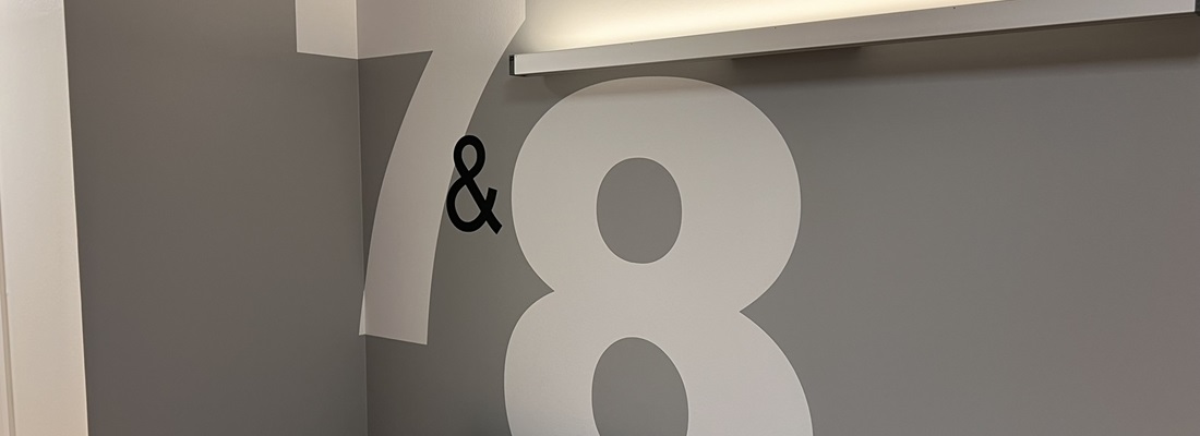 Wandgestaltung mit großen Zahlen 7 und 8 in Weiß auf grauer Wand – modernes Orientierungssystem von Folien Fischer Hamburg Bergedorf, Reinbek, Geesthacht, Lauenburg, Wentorf